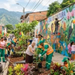 Ejemplos de RSE en Cali: empresas que están transformando la ciudad 3 Operarios ambientales de Veolia Cali y comunidad de Cali sembrando plantas y pintando un mural que dice De basural a jardín, representando proyectos de RSE y transformación urbana en Cali, Palmira, el Valle del Cauca.